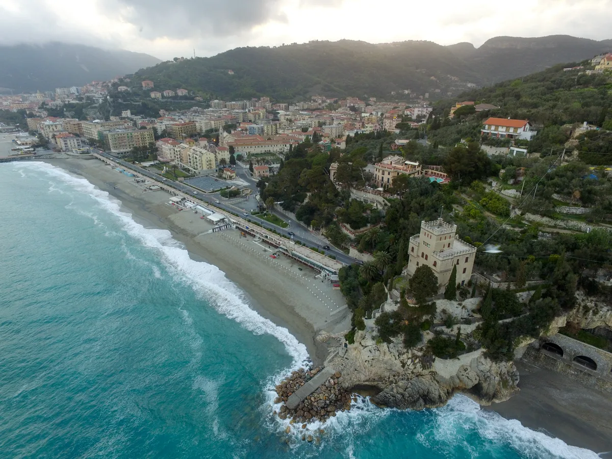 Luftansicht von Finale Ligure mit Strand, Küstenort und bewaldeten Bergen
